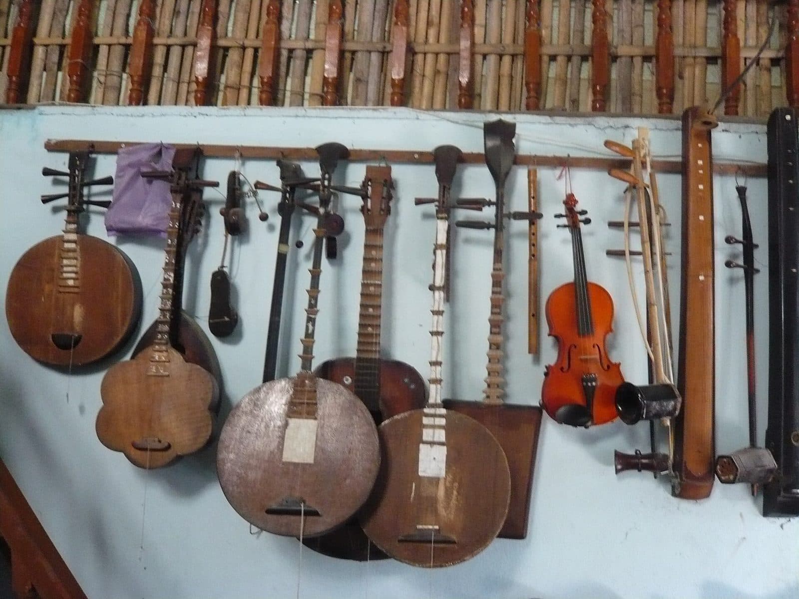 Hơn chục cây đờn treo trên vách: đờn kìm, đờn sến, đờn tam, sáo, violin, đờn cò